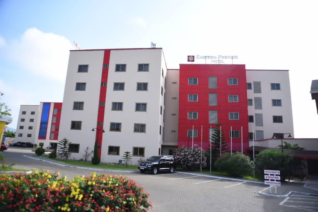 The Eastern Premier Hotel façade in daylight, with flowering gardens and parking